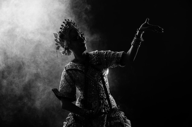 Half lichaam van Aziatische vrouw draagt Thaise traditionele kostuum danseres jurk silhouet schaduw Khon dans is Act Play Royal van Thailand over zwarte achtergrond rook