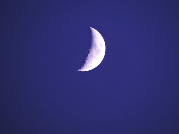 A half moon in a blue sky with a purple background