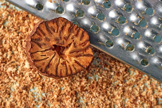 Half of nutmeg on a metal grater and grated nutmeg powder background