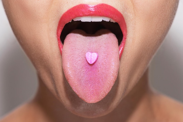 Фото Половина женского лица с таблеткой в форме сердца на языке
