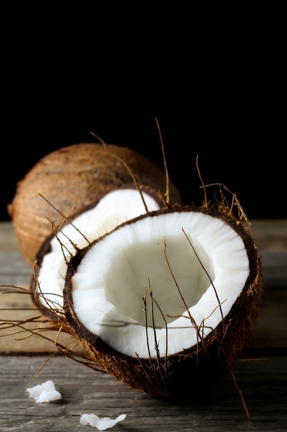 Half open coconut on wooden table, in dark mood