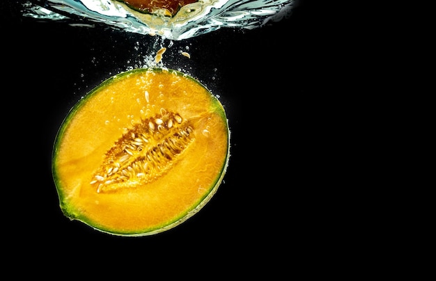 Half of Orange cantaloupe melon sinking and isolated on black