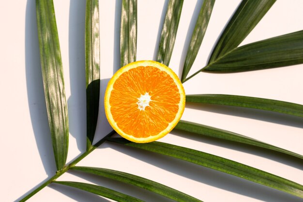 Half orange fruit on tropical palm leaves