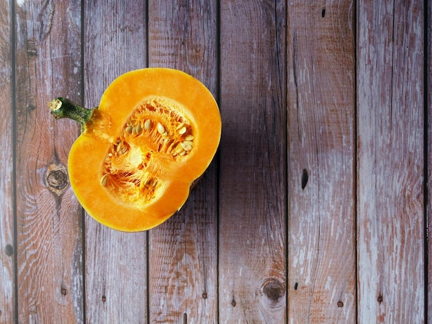 Half of an orange pumpkin on a wooden background Top view of cutaway fresh squash seeds pulp