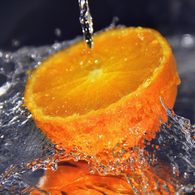 Половина апельсина с брызгами воды