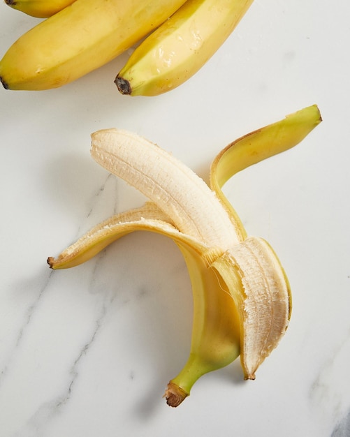 Half peeled ripe banana on white background