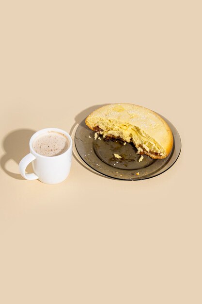 Half of a pie on a plate a cup of cappuccino on a beige background