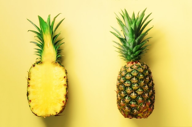 Half plakje verse ananas en heel fruit op geel