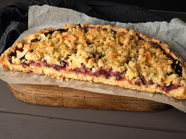 Half plum pie crumble on a brown wooden cutting board