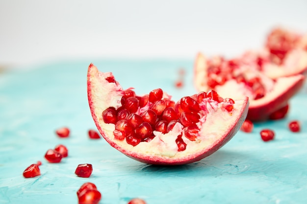 Foto mezza frutta del melograno su fondo blu. fresco rosso maturo