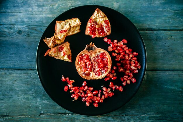 Half of pomegranate and pomegranate seed on black plate