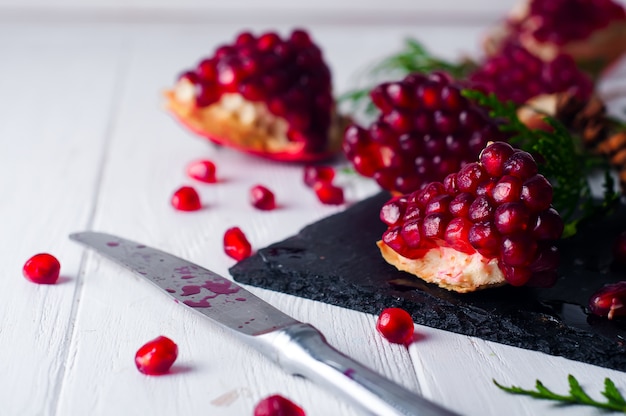 Half pomegranate and seeds a branch of spruce