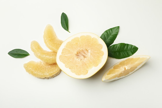 Half of pomelo fruit, slices and leaves on white