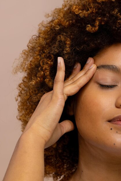 Half portrait of biracial woman with curly hair touching face with eyes closed