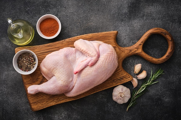 Half rauwe kip ingrediënten voor het koken van knoflookgroenten op een houten, rustiek bord, ongekookte kip bovenaanzicht