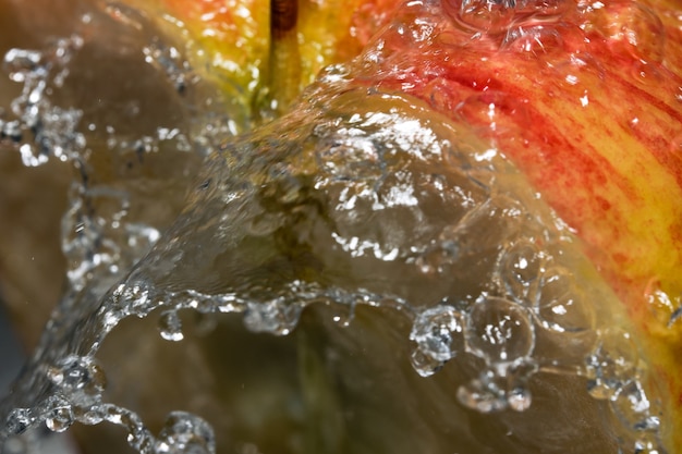 きれいな水のクローズアップマクロ写真の流れの下で赤い熟した甘いリンゴの半分