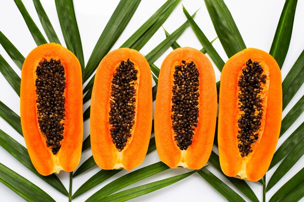 Half ripe papaya fruit on green leaves.