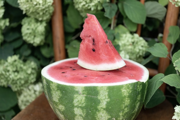 Half of ripe red watermelon and triangular slice of juicy ripe fruit on top ripe watermelon