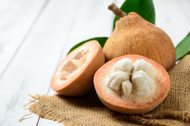 Half Santol op witte houten ondergrond, Santol heeft een zure smaak en het midden van Santol is zoeter. Het is een zeer bekende vrucht van de provincie Lopburi. THAILAND