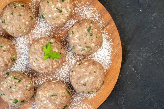 Half shot of uncooked meat balls with green in a brown plate on black background with free space in close up view