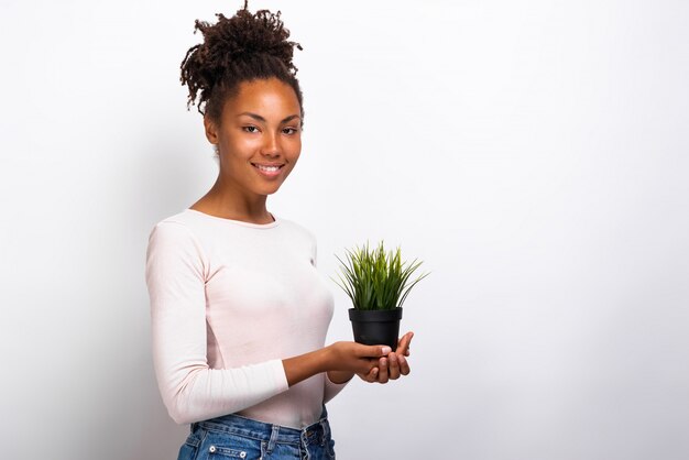 Half-turn portrait girl with grass pot in her hands. 