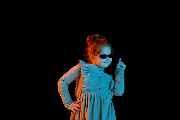 Halflength portrait of cute redheaded little girl wearing festive dress isolated over dark