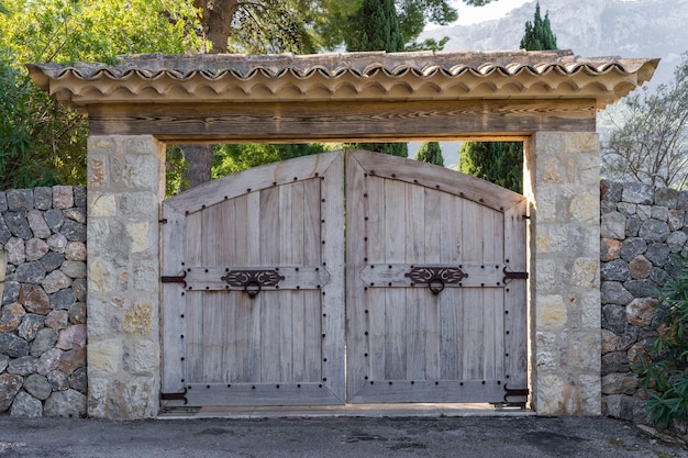 Halfronde houten poort met smeedijzeren deurhandgrepen en scharnieren tegen een achtergrond van bergen