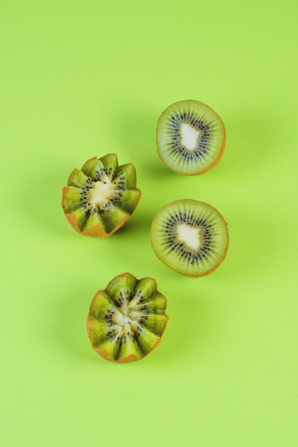 Halfs of a green ripe kiwi on a green background, top view, monochrome