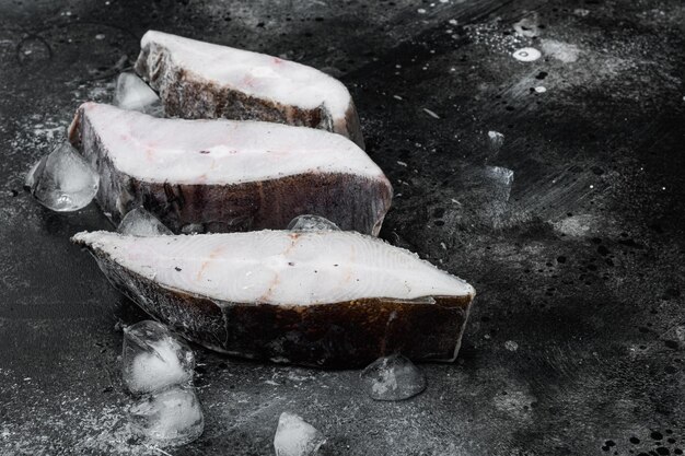 Bistecca congelata di pesce ippoglosso su sfondo nero tavolo in pietra scura