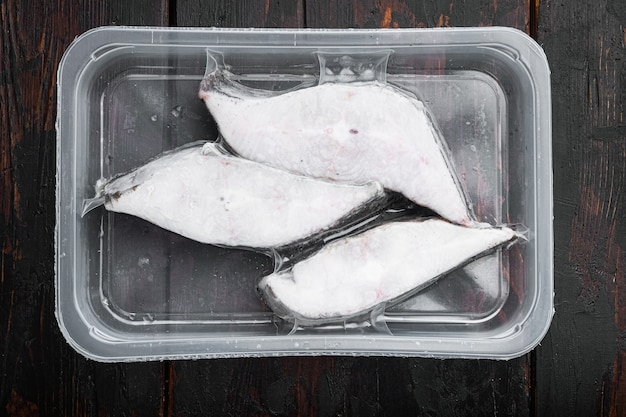 Halibut fish frozen steak pack set, on old dark wooden table\
background, top view flat lay