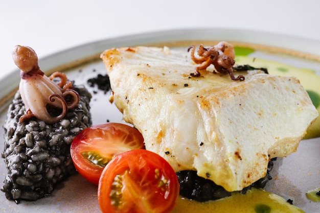 Foto halibut con risotto nero e polpo