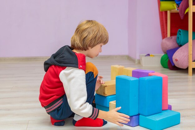 In the hall the child collects toy cubes the boy plays in the hall with sports items