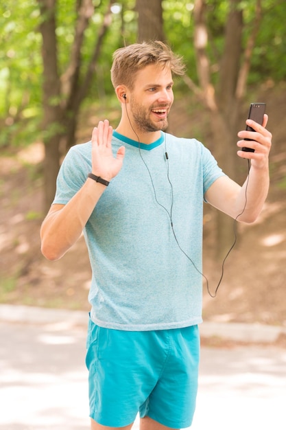 Hallo daar Fitnessblog Fitnessdoelen bereiken Sportman die videogesprek voert met mobiele telefoon Atletische man die telefoon met luidsprekermodus gebruikt Overal verbonden Fitness blogger streaming workout