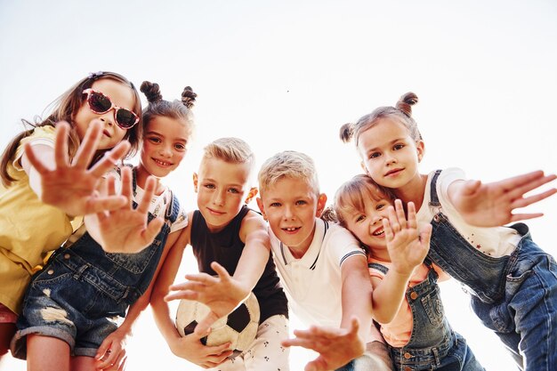 Hallo, gebaar. Met voetbal. Portret van kinderen die samen staan en poseren voor de camera.