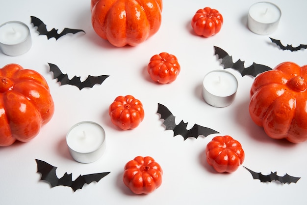 Halloween achtergrond, oranje decoratieve plastic pompoen zwart papier vleermuis ronde kaars wit karton Thanksgiving wenskaart patroon