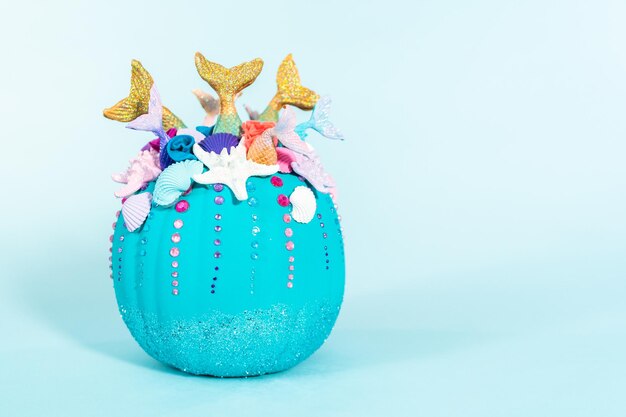 Halloween ambachtelijke pompoenen versierd met zeemeerminstaarten, glitter en sprankelende strass-steentjes op een blauwe achtergrond.