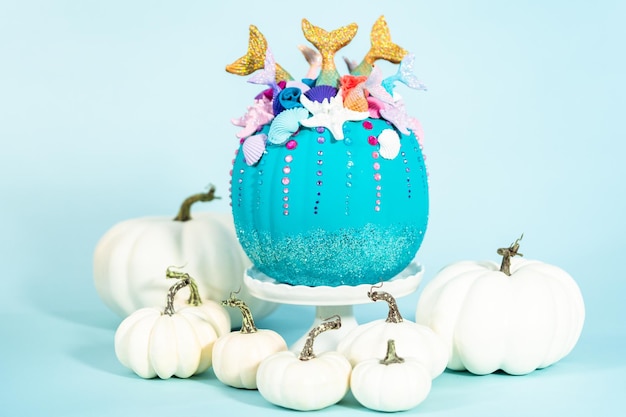 Halloween ambachtelijke pompoenen versierd met zeemeerminstaarten, glitter en sprankelende strass-steentjes op een blauwe achtergrond.