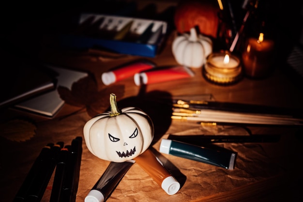 Halloween arts and crafts painting pumpkins brushes and paints on the table on dark night close up