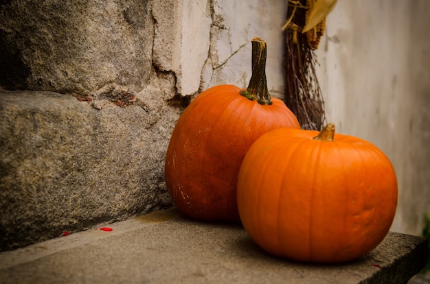 Halloween autumn holiday decoration at the stone stairs. Red pumpkins against grunge wall, seasonal background