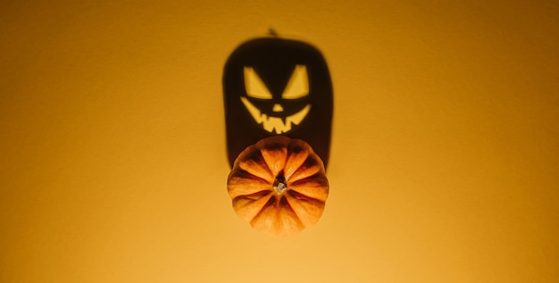 Halloween background concept. Jack O pumpkin angry face shadow. Spooky smiling shadow of an orange pumpkin lantern top view close up, Halloween party design