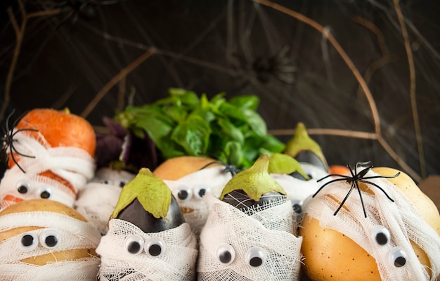 Halloween background. Creepy vegetables with eyes in medical bandages on a dark background. Halloween food. Baner. Copy of the space.