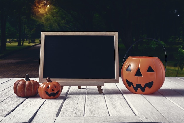 Halloween background. Spooky pumpkin, chalkboard on wooden floor and dark forest. Hallowee