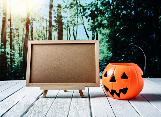 Halloween background. Spooky pumpkin, chalkboard on wooden floor and dark forest