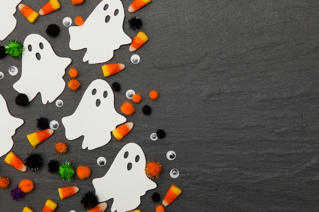 Halloween background with ghosts and candy corn on a slate background