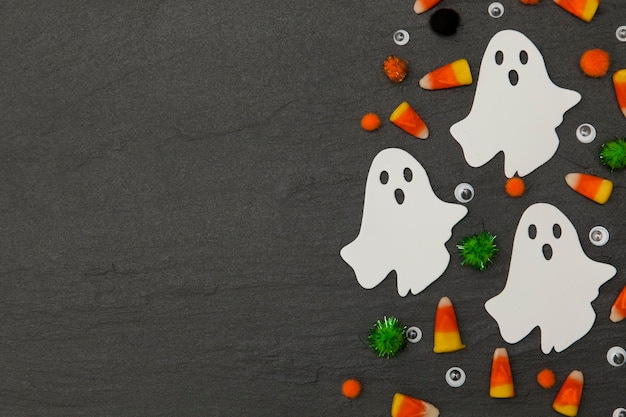 Photo halloween background with ghosts and candy corn on a slate background