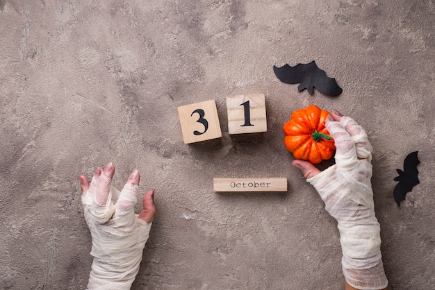 Halloween background with mummyÃ¢ÂÂs hands and wooden calendar