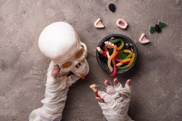 Sfondo di halloween con le mani, i dolci e il cranio della mummia