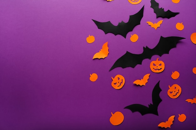 Halloween background with paper pumpkins, jack o lantern black orange bats flying over purple background, copy space