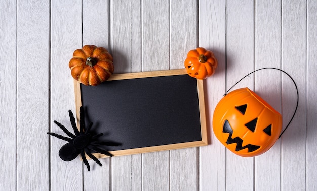 Halloween background with Pumpkins, black spider and chalkboard on wooden