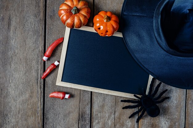Halloween background with Pumpkins, Witch hat, Black spider, fingers and chalkboard on woo